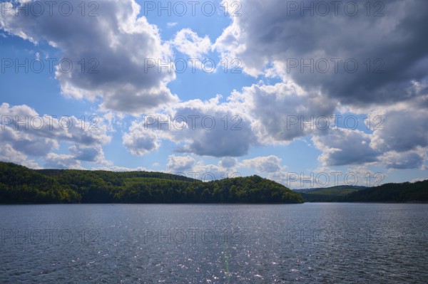Blue sky with clouds over a calm, glittering lake and wooded hills, summer, Rursee, Rurtalsperre,