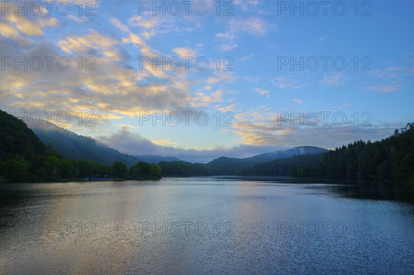 Gentle morning colour reflected on the quiet lake, surrounded by hills and clouds, summer, Rursee,