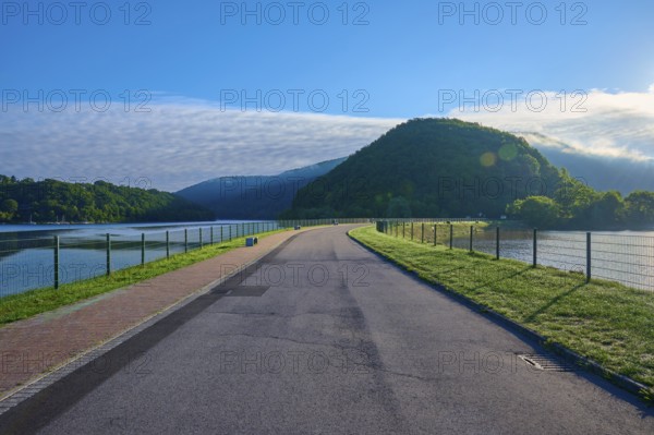 Paulushof barrier dam, dam road along a lake in a mountainous landscape, morning light and clear