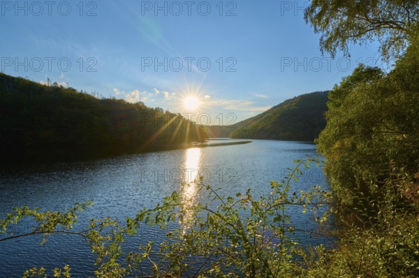 Sunset reflected in the lake, surrounded by forest and hills, summer, Rursee, Obersee, Simmerath,