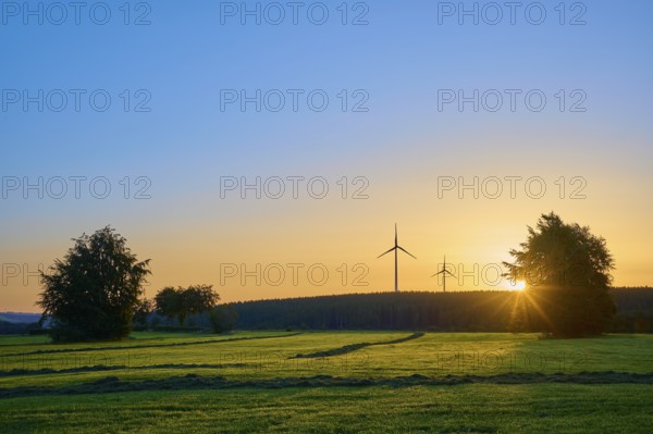 Wind turbines in a natural landscape at sunrise, with warm incidence of light, summer, Rohren,