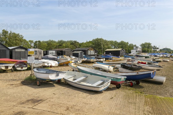 Dinghies on beach with black fishing sheds and Riverside Tearoom cafe, Orford, Suffolk, England, UK