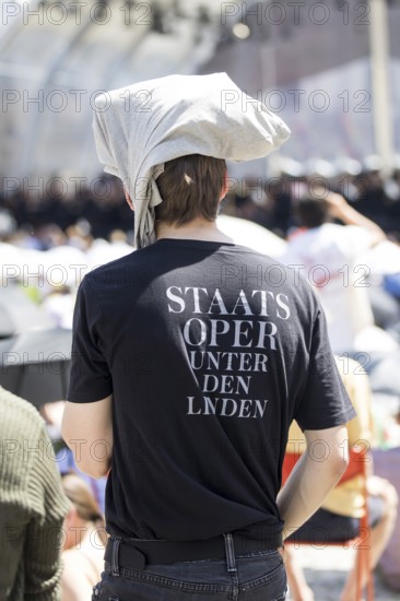 A visitor protects himself from the sun with fabric on his head at the Staatsoper fÃ¼r alle, a free