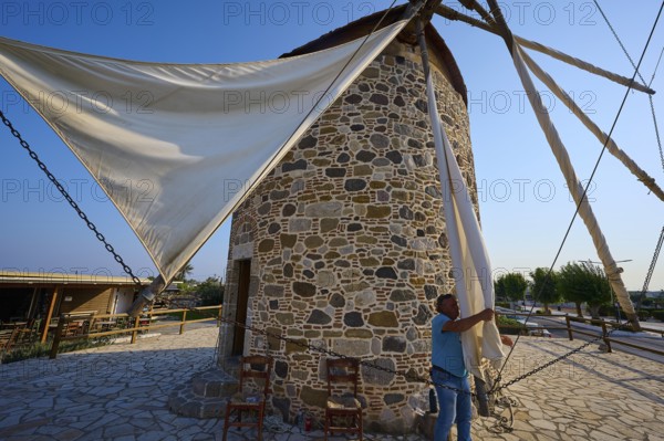 Stone windmill in summer light, a man fastening a sail, windmill, Antimacheia, Kos, Dodecanese,
