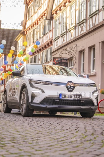 Car in a narrow alley in the old town centre, surrounded by half-timbered houses and lanterns in a