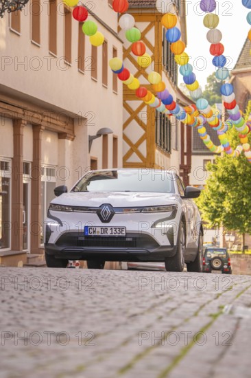 Car in a cobblestone alley decorated with colourful lanterns under bright daylight, Deer E, car