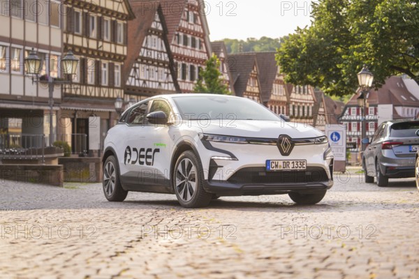 Car on a cobbled square surrounded by half-timbered buildings, summer atmosphere in the early
