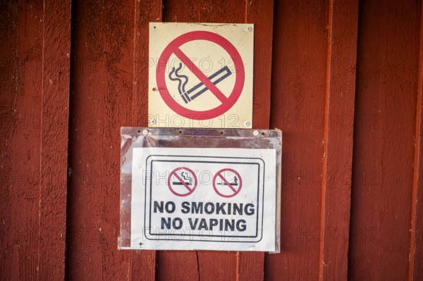 Red wall with no smoking signs prohibiting smoking and vaping, Svedjehamn, Kvarken Archipelago,