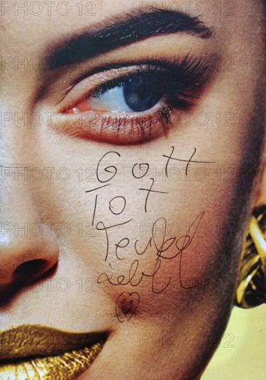 Large-scale advertising poster depicting a woman's face and the inscription Gott tot, Teufel lebt,