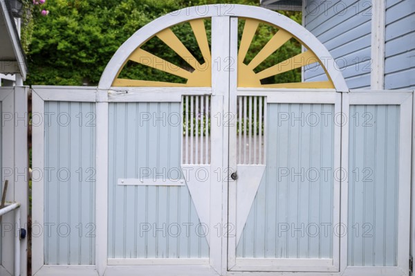 Street scene in the old town of Naantali, a decorative wooden gate in pastel shades with a
