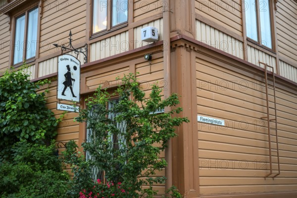 Street scene in the old town of Naantali, orange-painted wooden house with road signs and lush