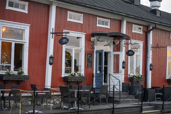 Red wooden café building with outdoor seating area, inviting and traditionally designed, Naanatali,