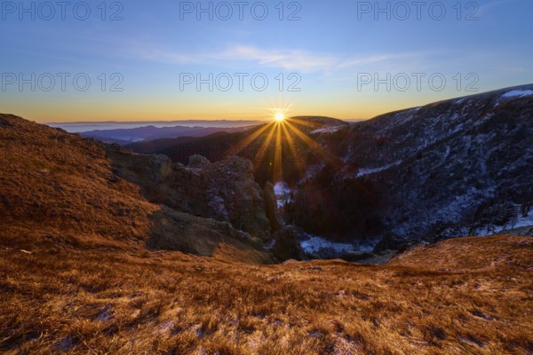 Golden sunbeams over mountain landscape under clear blue sky, looking towards the Rhine Valley,