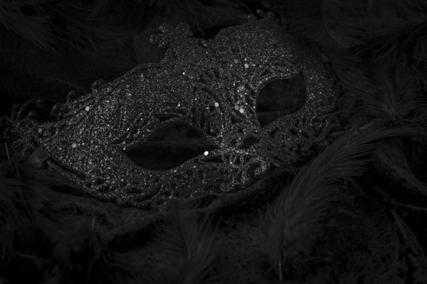 Black mask on dark background, contrasting carnival atmosphere