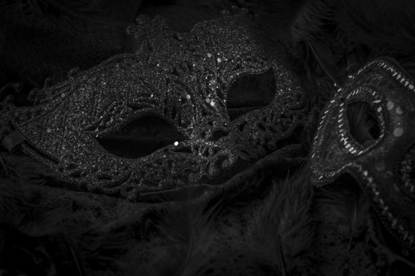 Black masks on a dark background, contrasting carnival atmosphere