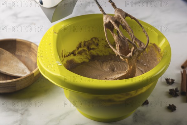 Electric mixer processes cocoa dough in a yellow bowl