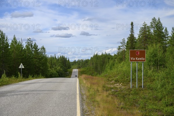 Via Karelia country road with a sign and surrounding trees under blue sky, Kuusamo, Lapland,