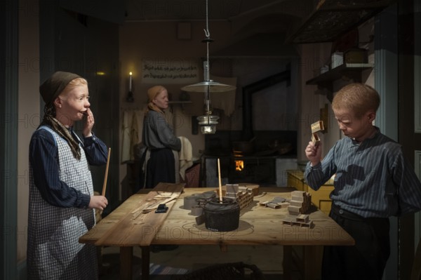 Children glue matchboxes together while working from home, child labor, historical scene recreated,