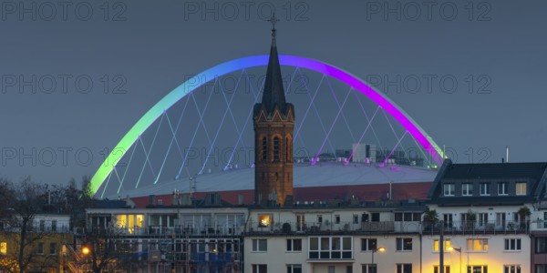 Evening view of residential buildings on the banks of the Rhine, behind them the church tower of St