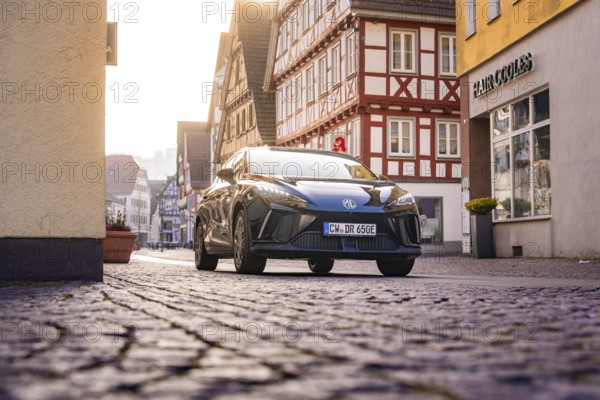 Black car in an almost empty cobblestone street in the old town, MG4 electric car, Deer