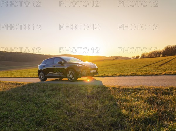 The car is parked on a country road at sunset, with wide fields dominating the scene, MG4 electric