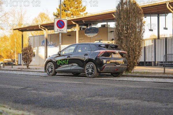Car parked near an outdoor pool building with evening lights and signs, MG4 electric car, Deer