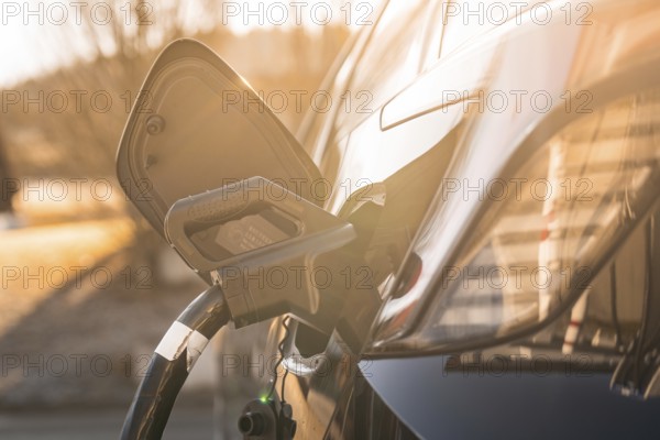 Electric car at a charging station at sunset, modern design emphasized by lighting, MG4 electric