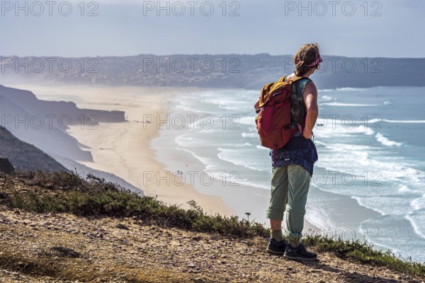 Woman with backpack, above beach Prai de Bordeira north of village Carrapateira, coast of western