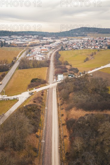 Aerial view of a railway line through snowy fields near a village, using a tamping machine at the