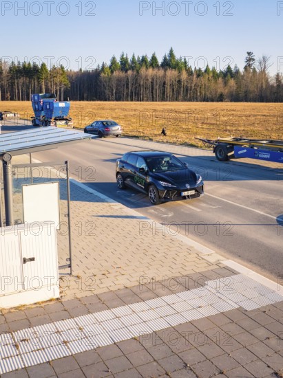 A car moves on a road flanked by other vehicles and trees, MG4 electric car, Deer e-Carsharing,