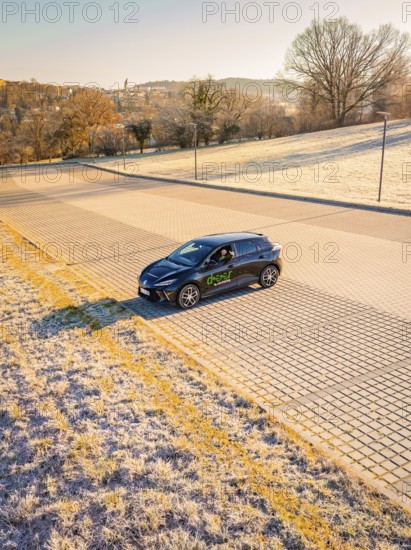 Car driving on a frosty road surrounded by early morning sunlight, MG4 electric car, Deer