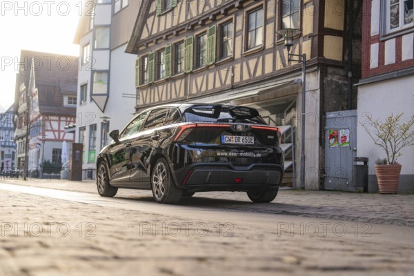 Rear view of a black car in front of historic half-timbered houses, captured in the evening mood,