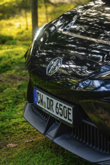 Close-up of a car in a forest clearing in sunlight, MG4 electric car, Deer e-Carsharing, Calw,