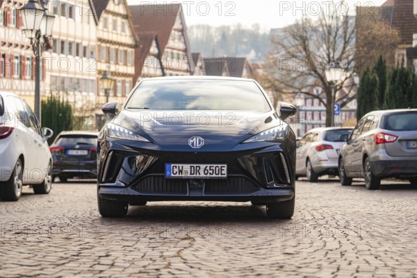 A car in an old town street with half-timbered houses and cobblestones, MG4 electric car, Deer
