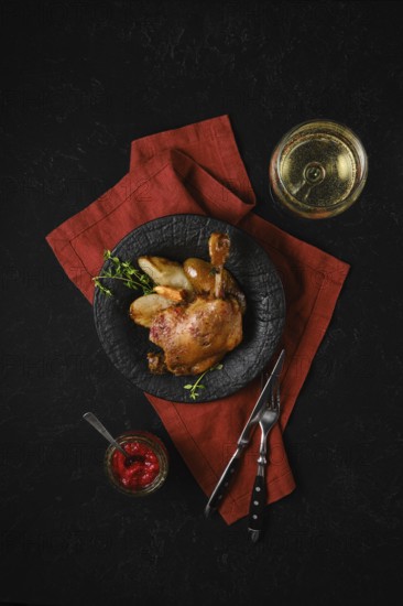 Top view of a plate with roasted duck leg along with caramelised pears and fresh thyme served with