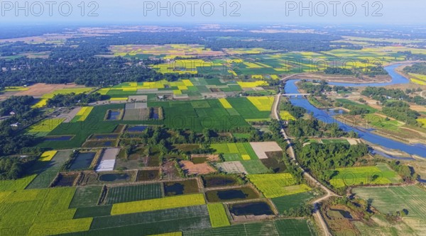 An aerial view reveals a gently curving river winding through the countryside, its silvery surface
