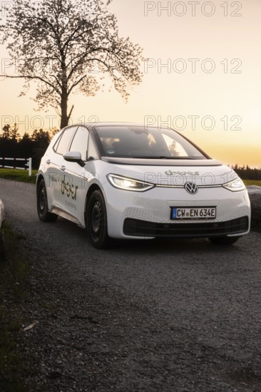 Car at sunset on street, parked with illuminated headlights, VW ID3 electric car, deer e-car
