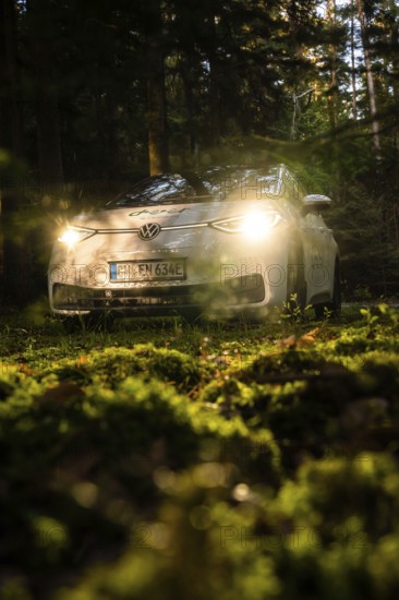 Car in the dark forest, headlights glow on mossy ground, mystical atmosphere, VW ID3 electric car,