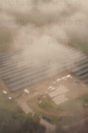 Construction site for solar systems, foggy environment with several construction site vehicles,