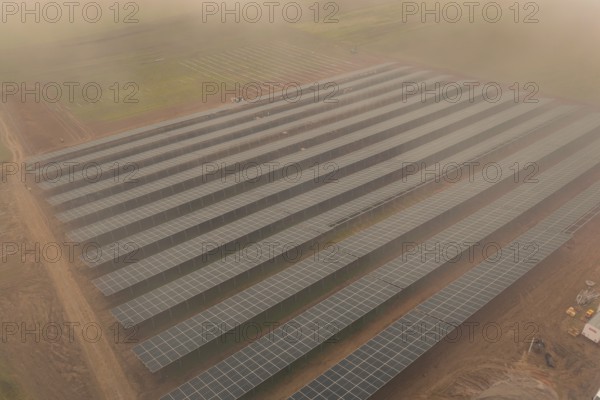 Dense rows of solar panels on foggy field, clear lines and structure, energy revolution,