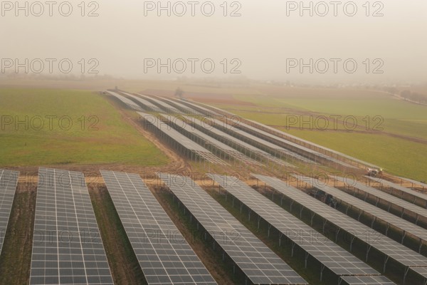 Rows of solar panels on vast green fields, focus on sustainability, energy transition, construction