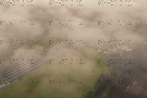 Solar systems in a foggy field landscape, diffuse view through thick fog, energy revolution,