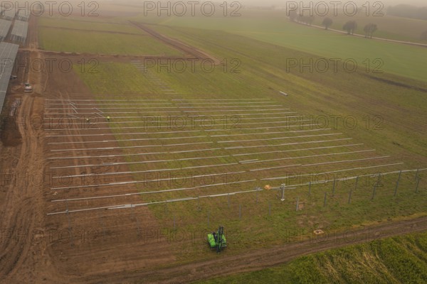Foggy fields with solar system installation in the foreground, machines in use, energy revolution,
