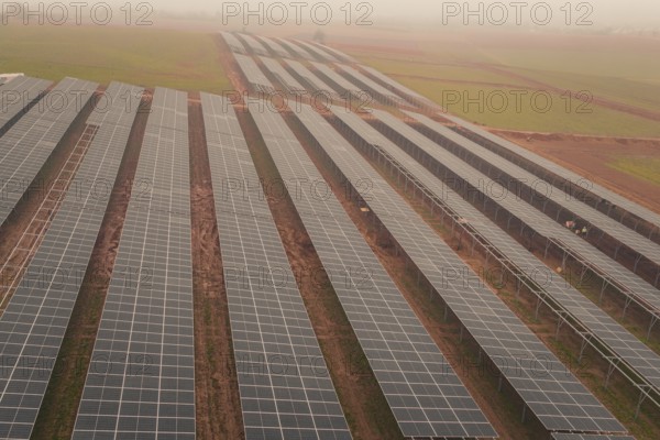 Extensive solar panel layout in foggy landscape, sustainable energy source, energy transition,