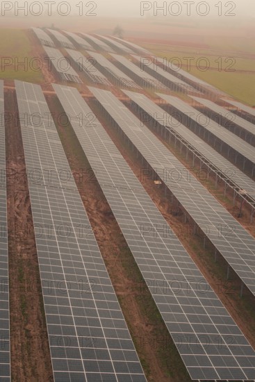 Row of solar panels in a foggy landscape, sustainable energy generation in wide fields, energy