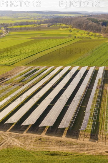 Aerial view of solar panels in an agricultural environment with vast green fields, energy