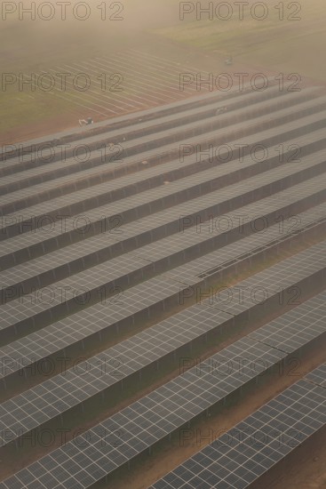 Arranged rows of solar panels on field, foggy atmosphere with structured pattern, energy