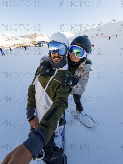 Couple having fun snowboarding on a sunny winter day, enjoying their active vacation in the snow