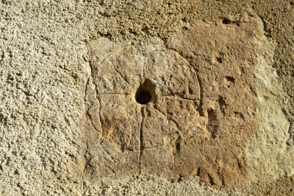 A close view showing a medieval mass dial carved into the exterior wall of St. Saturninus Church.