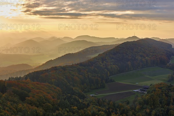 View of an autumnal forest from the Gisliflue, behind the Jurassic foothills with the water fluh in